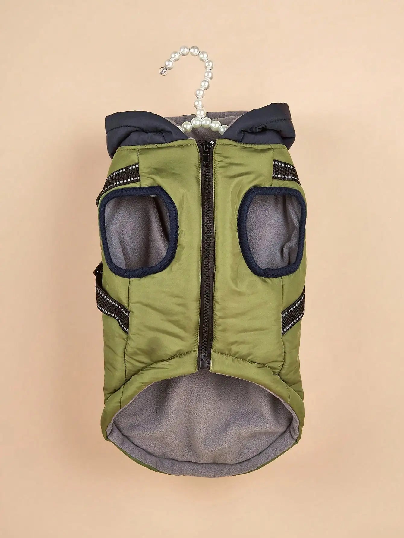 Green dog coat with black accents on a beige background