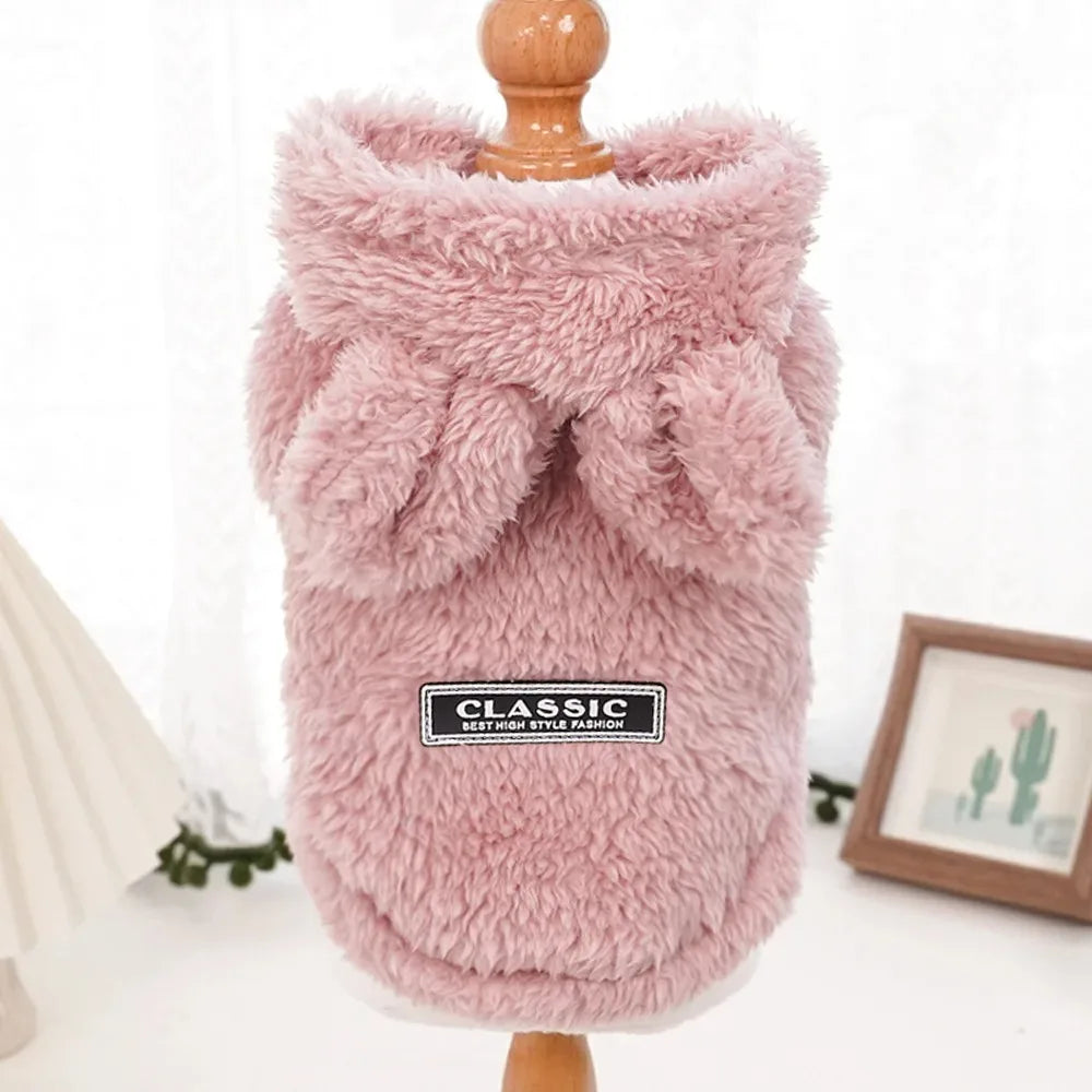 Pink fluffy pet coat on a wooden stand with a white background
