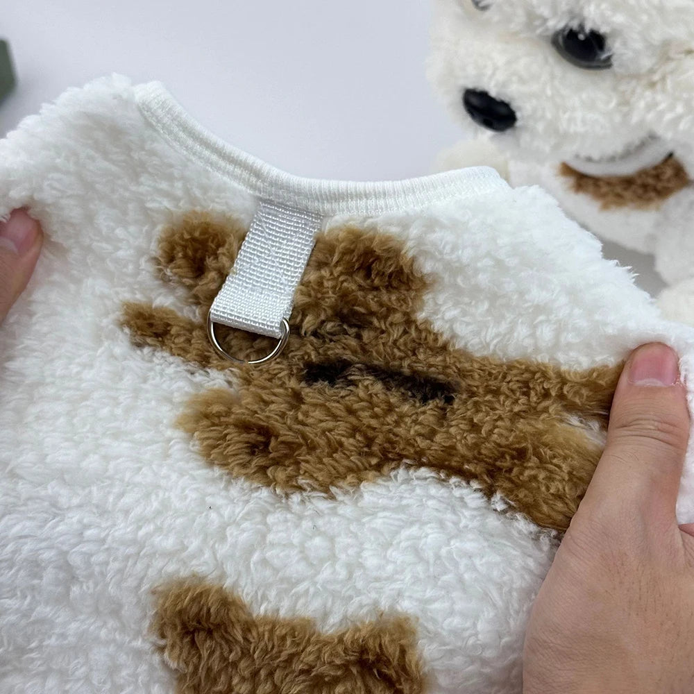 Close-up of a fluffy white and brown plush toy with a hand holding it.