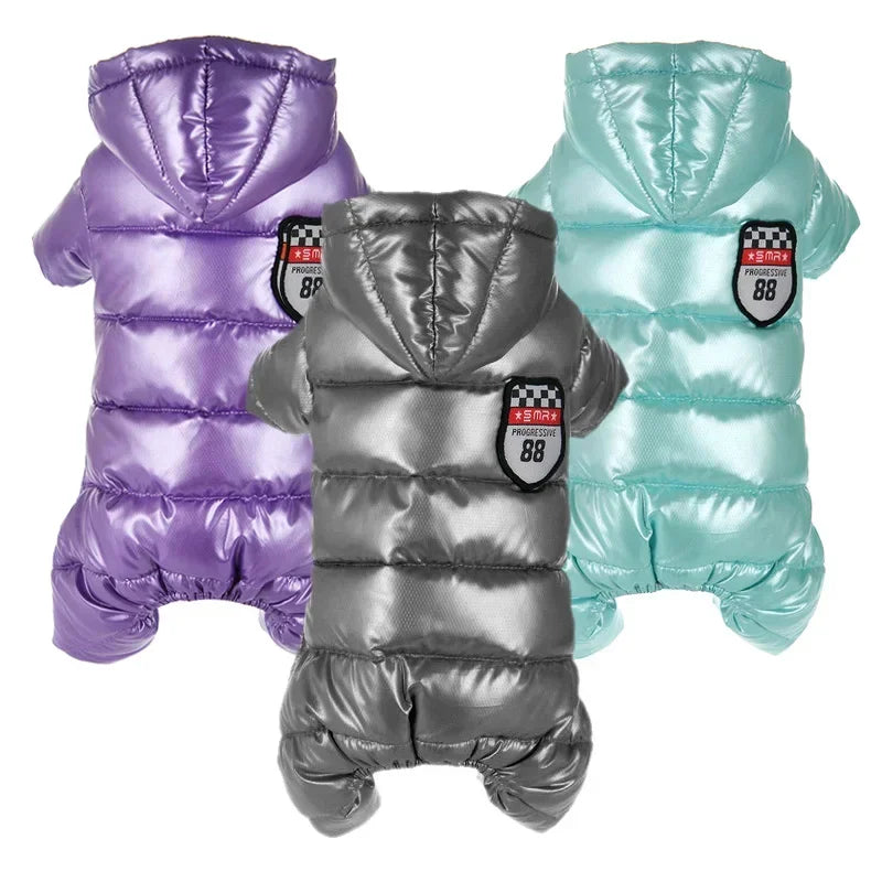 Three metallic dog coats in purple, silver, and teal on a white background.
