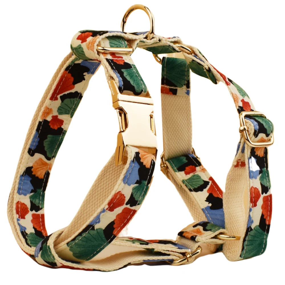 Dog harness with colorful floral pattern and gold hardware on a white background